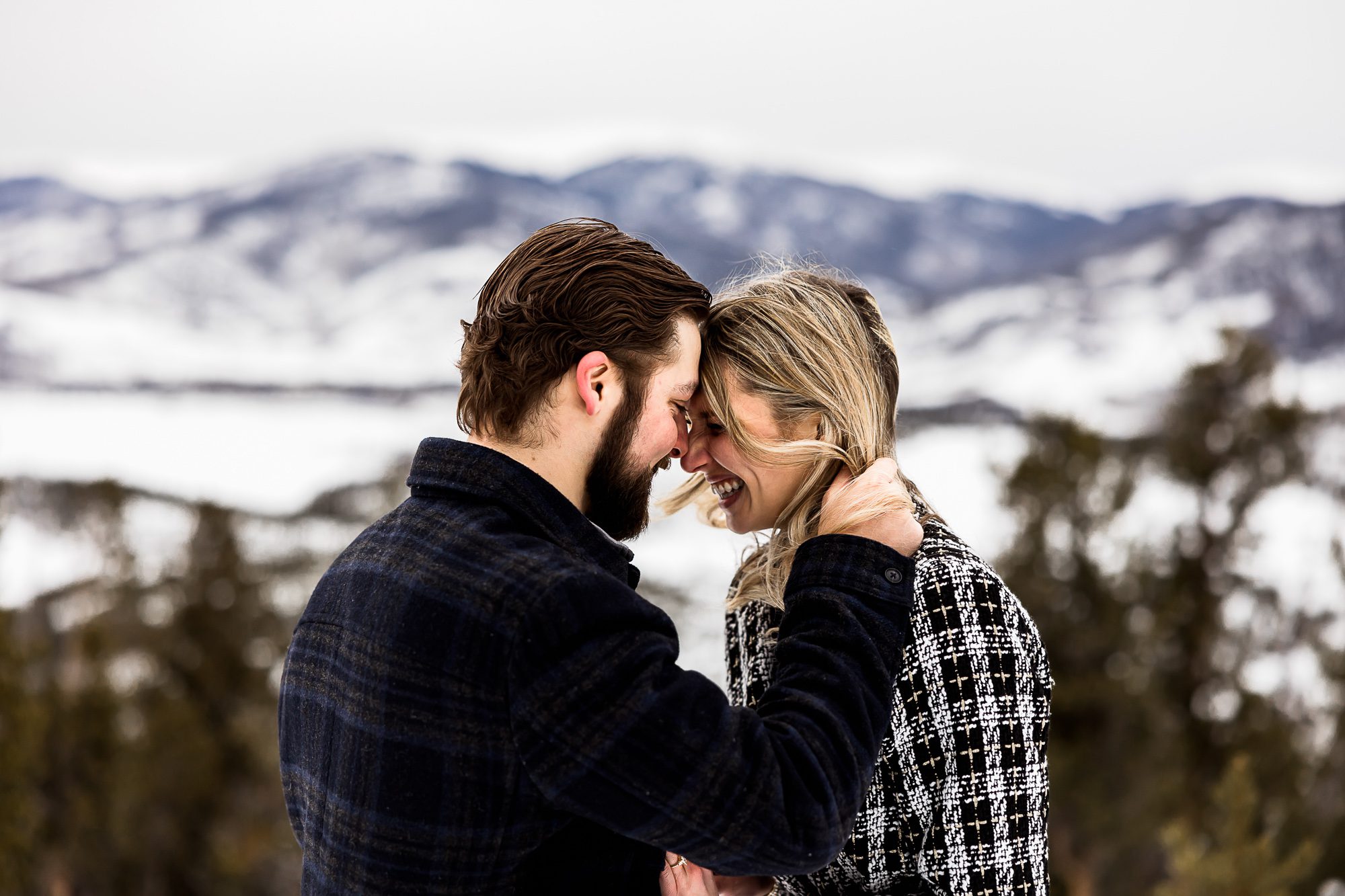 Surprise proposal in the mountains, man running fingers through his fiancé's hair