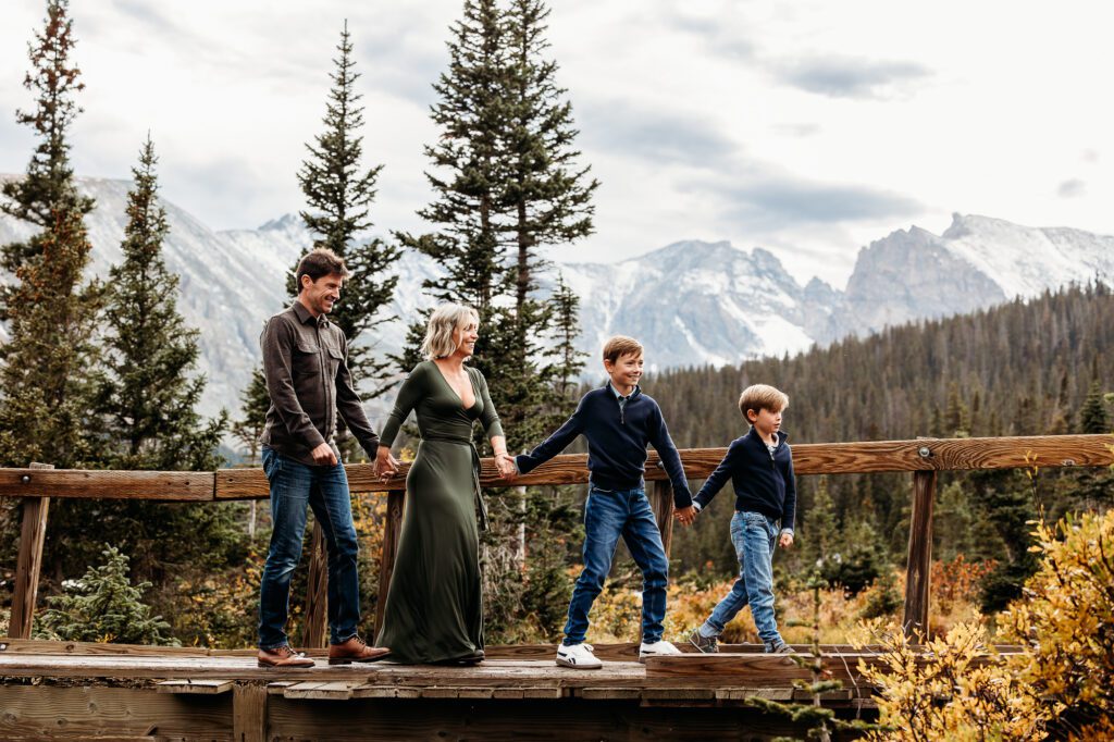 Family of four walking across wooden bridge at Brainard Lake in the Indian Peak Wilderness for their Fall Family Pictures with Colorado Lifestyle Photography